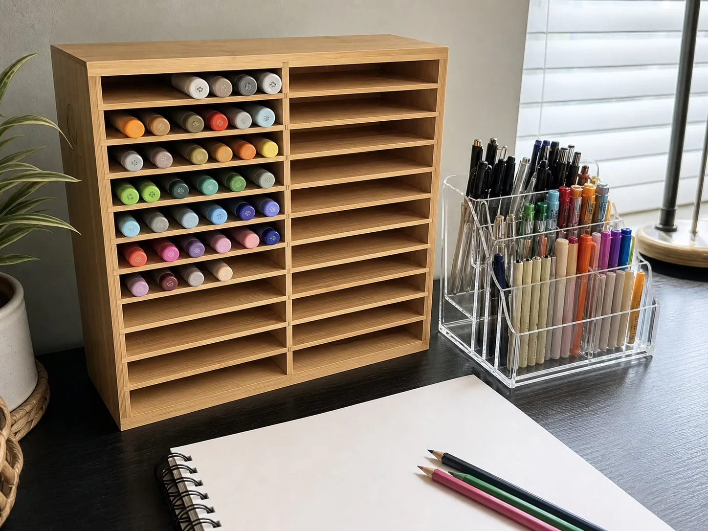 Bamboo horizontal marker rack beside a clear acrylic pen holder on an adult craft desk