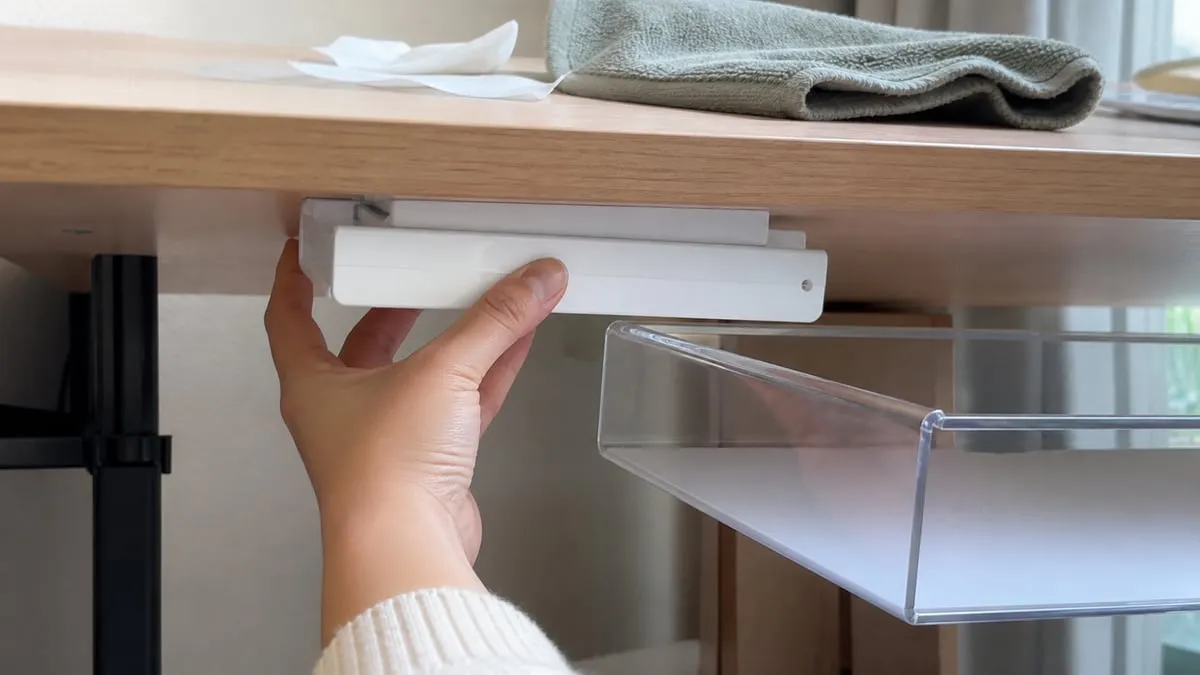 Pressing the white mount onto the underside of a light wood desk