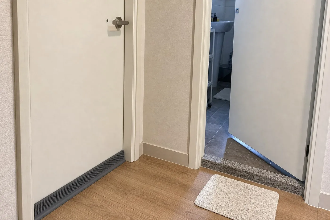 A hallway where one interior door has a grey bottom strip while a nearby bathroom or utility door keeps its lower airflow gap open