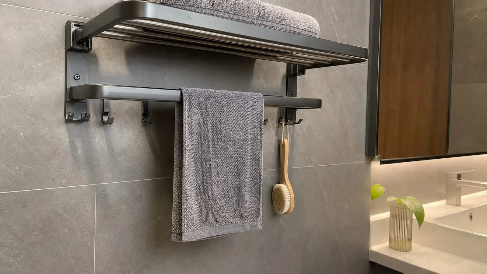 A towel rack shelf with a loosely folded towel above and airflow around a hanging hand towel