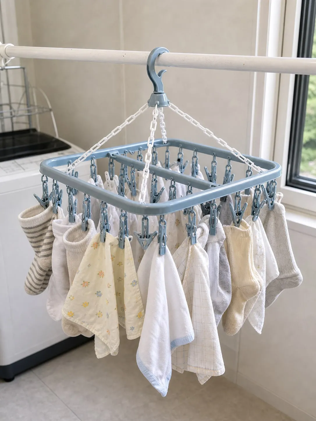 A pale blue square multi-clip drying hanger hanging level with socks and handkerchiefs spread across both sides