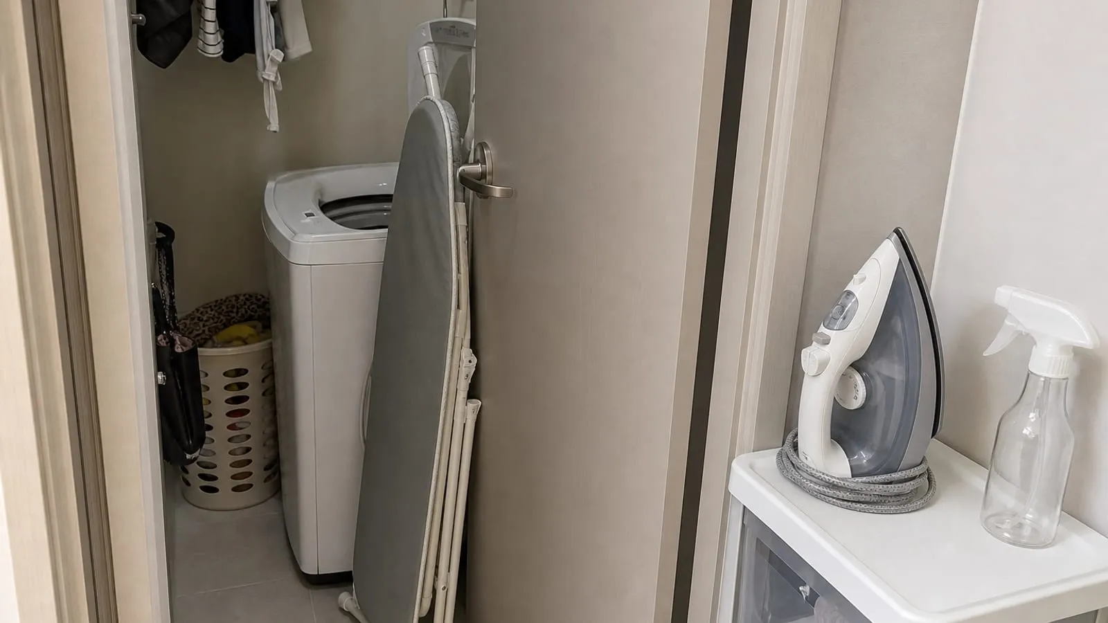 A folded ironing board leaning awkwardly behind a narrow laundry room door