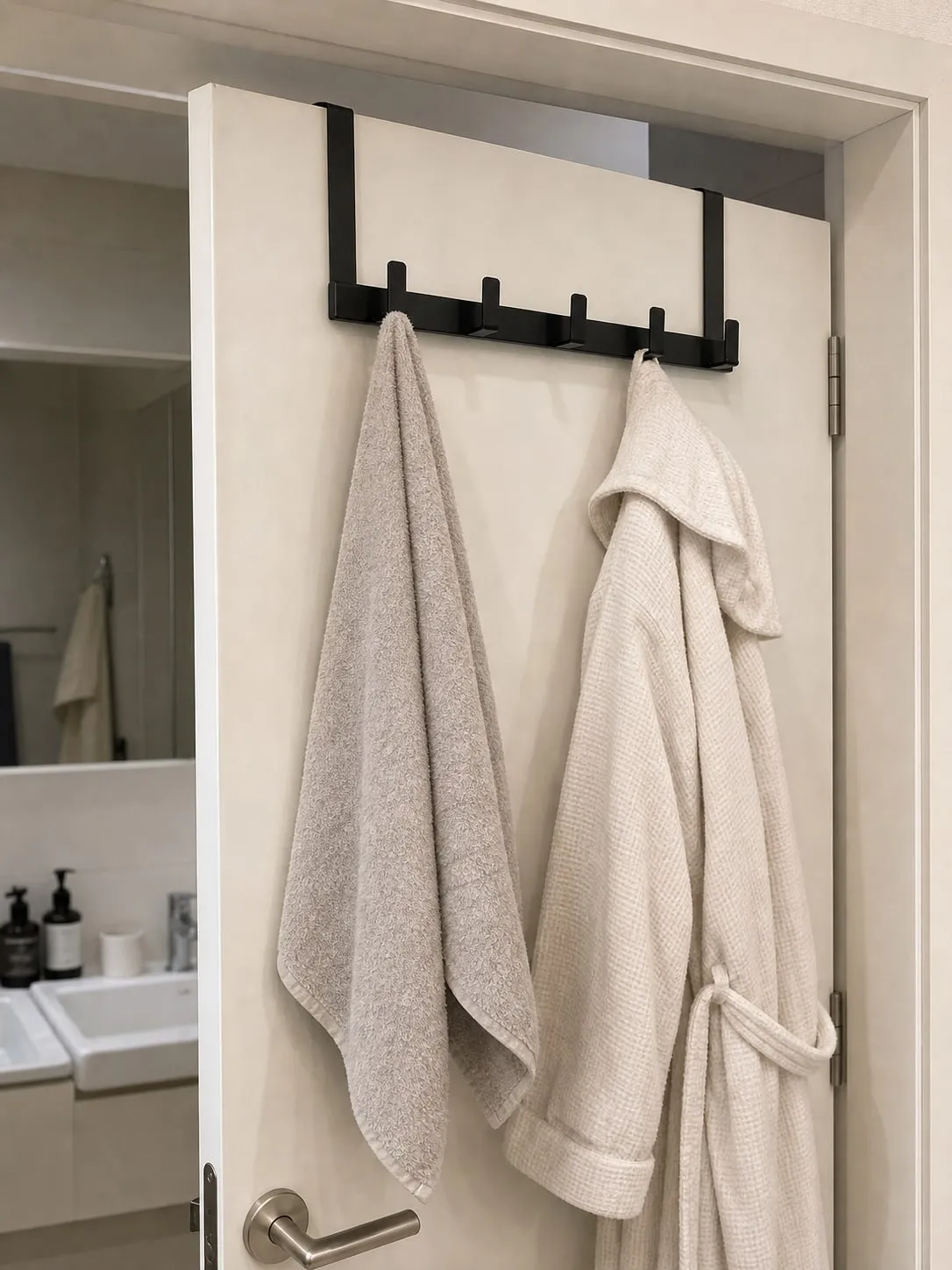 A black over-door hook rack on a white door partly closing with the top bracket and clearance visible
