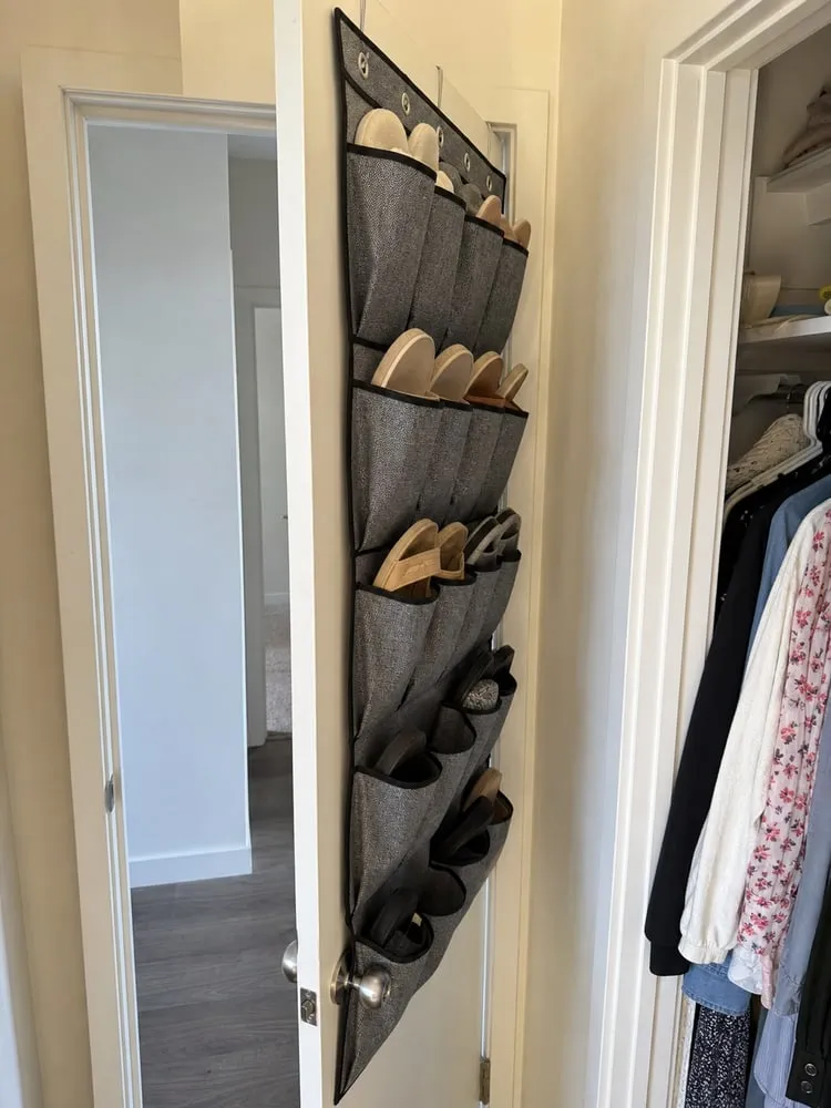 A partly open closet door with a grey over-door shoe organizer showing how the pockets protrude behind the door