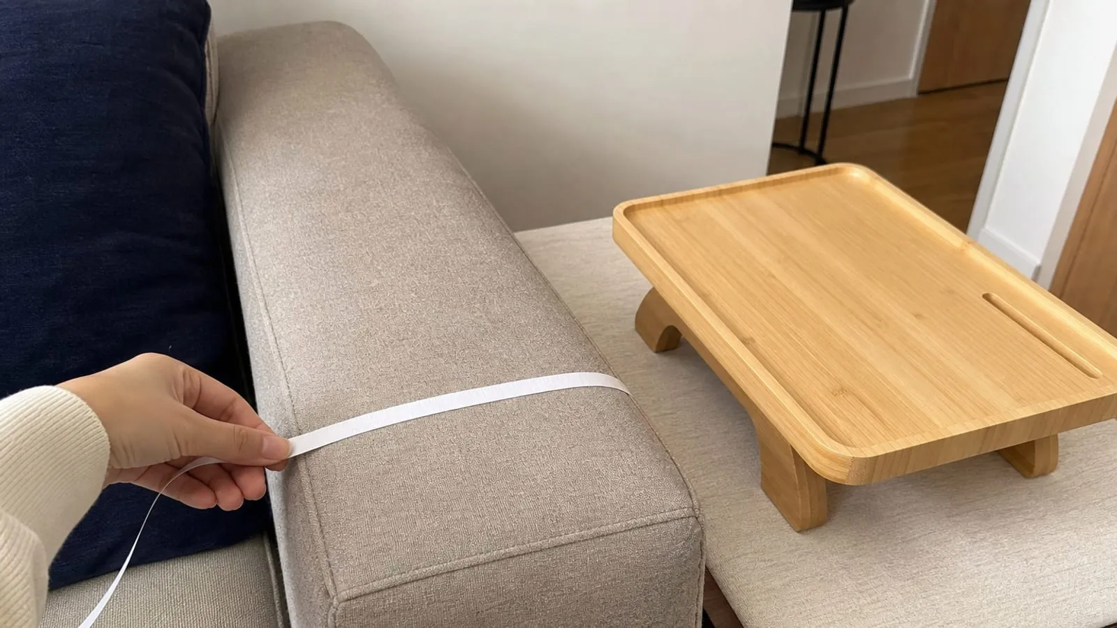 Measuring a sofa arm before placing a wood sofa-arm tray beside it