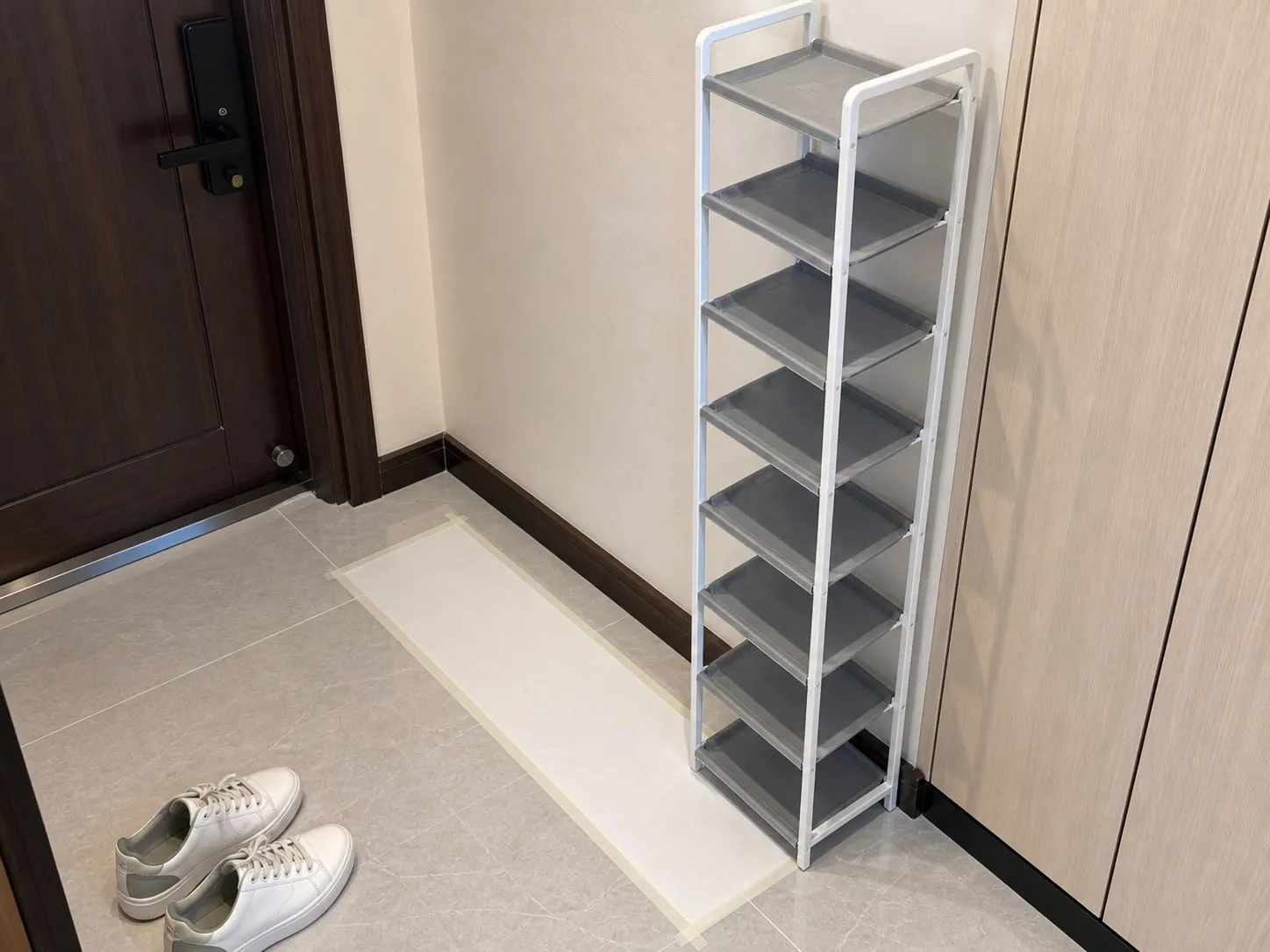 Testing the footprint of a narrow shoe rack beside an apartment door and shoe cabinet area