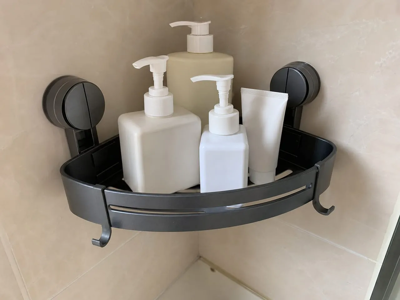 Suction-cup triangular shower caddy installed on a smooth tiled bathroom corner