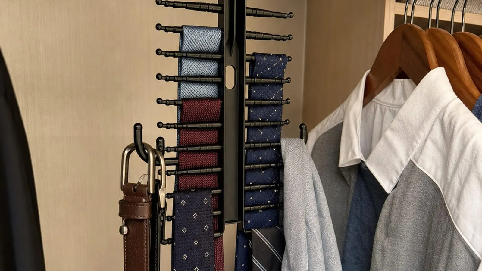 Black multi-row tie and belt rack hanging inside a closet with ties and belts separated