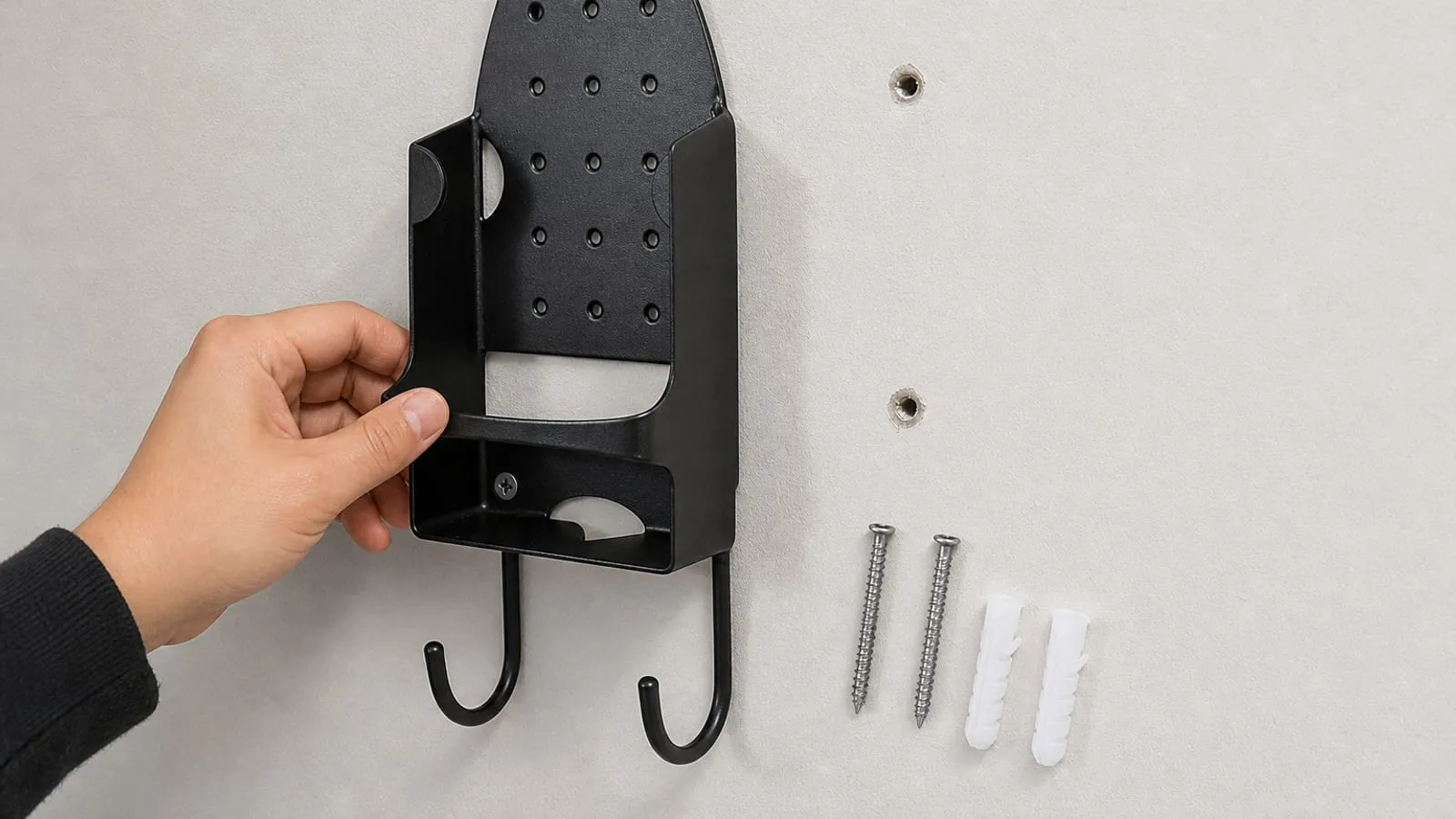 A close view of a black iron holder being aligned with screws and anchors on a wall