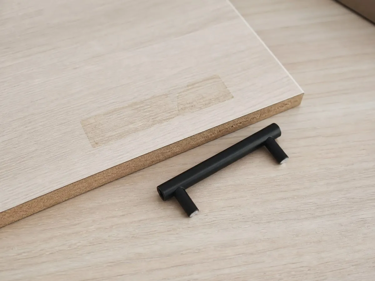 A removed adhesive pull handle beside a sample board with a faint rectangular sticky residue mark