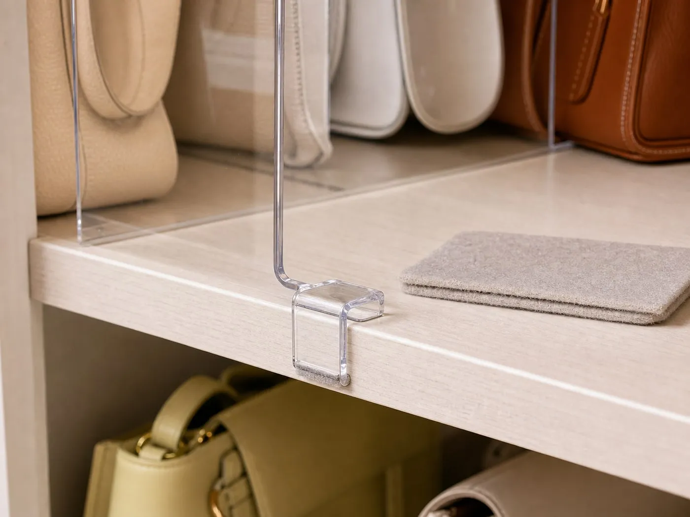 A clear divider clip on a shelf edge with a small soft pad nearby for finish protection