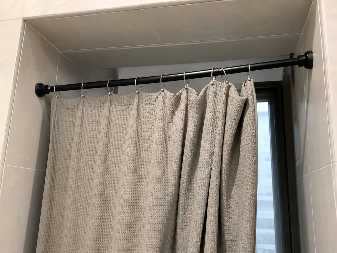 Tension rod sitting slightly lower on one side under a heavier curtain