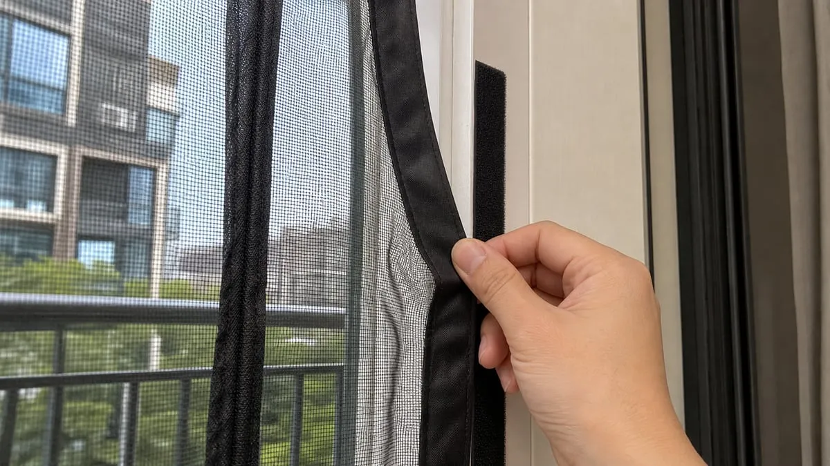 Pressing the mesh border onto hook-and-loop tape on a door frame