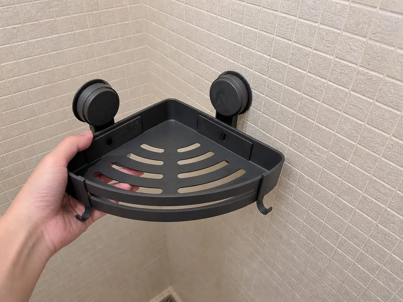 Holding a suction-cup shower caddy near small textured tiles with many grout lines