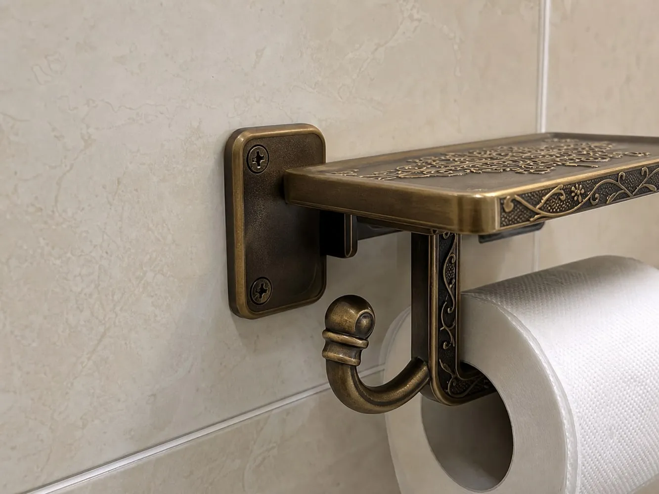 A close view of the wall plate and screw area on a shelf-style toilet paper holder
